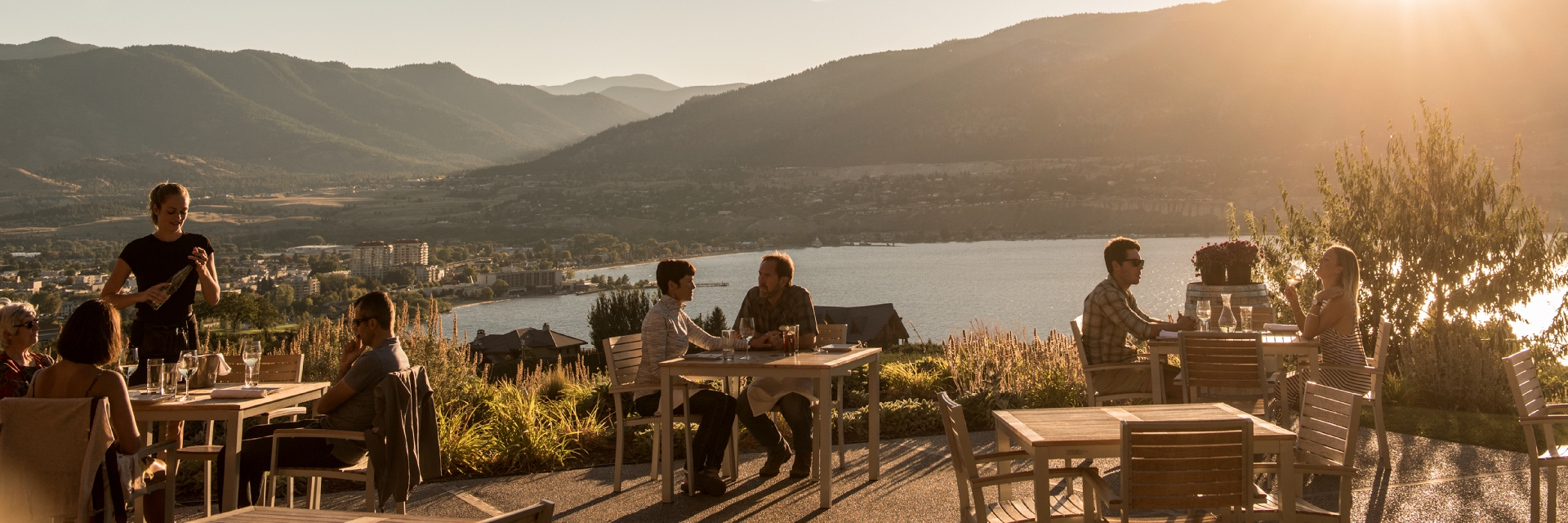 Patrons of The Vanilla Pod Restaurant at Poplar Grove winery enjoy dining on the patio with views of Okanagan Lake and Penticton, BC.
