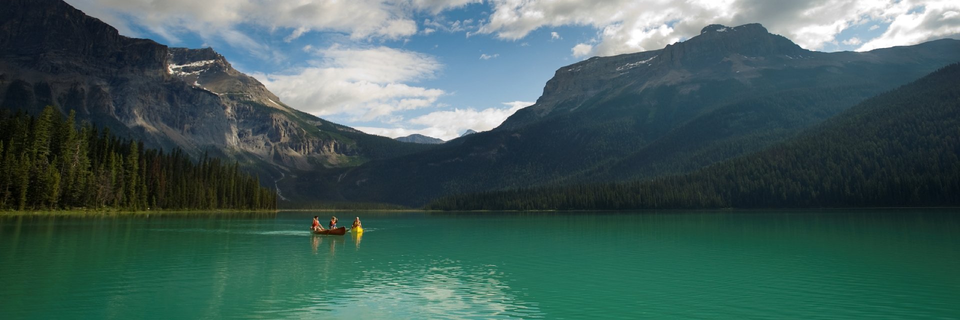 Two couples canoeing on Emerald Lake with views of the mountains in Yoho National Park near Field.