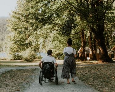 Person walking and person using a wheelchair near the Maple Bay cabins at Cultus Lake Provincial Park