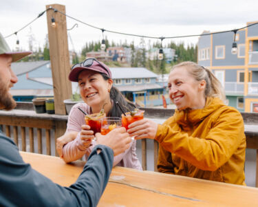 People at Black Pine restaurant on SilverStar Mountain Resort enjoying time on a patio table toasting
